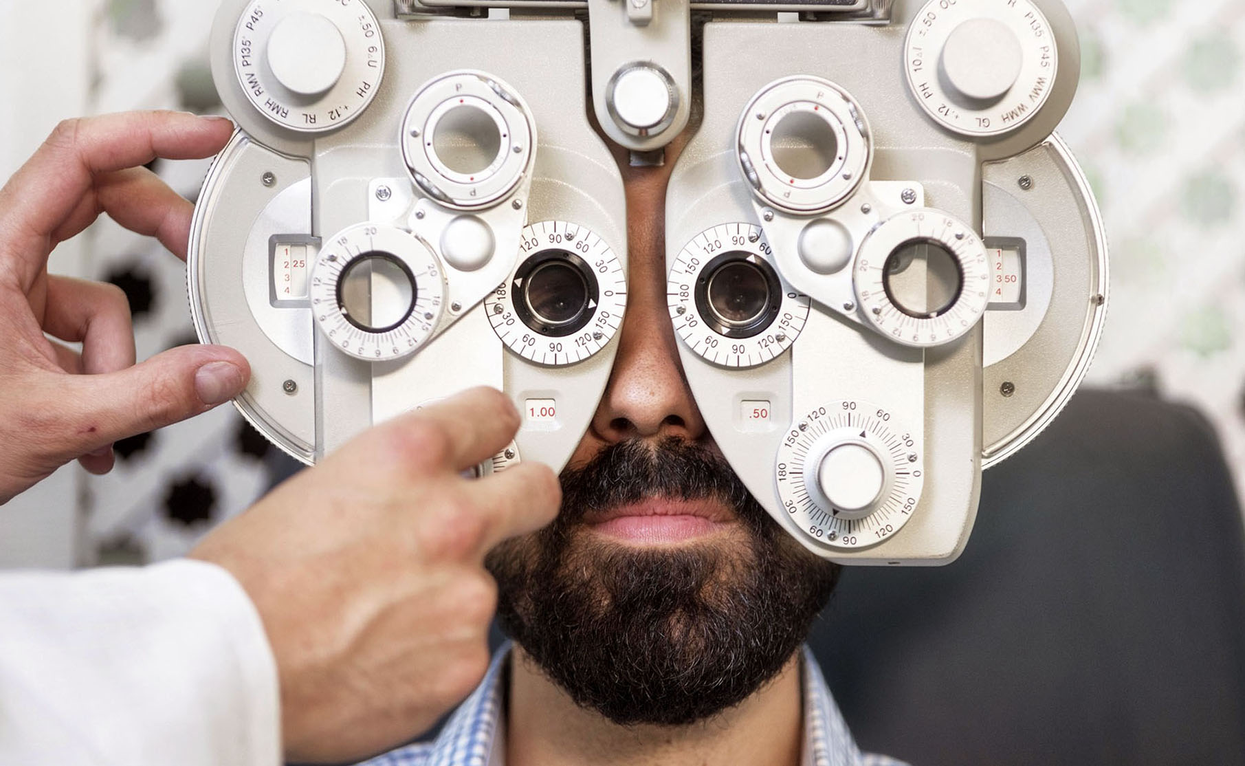 Optometrist doing sight testing for male patient In clinic. Male ophthalmologist examining patient man with optometrist trial frame