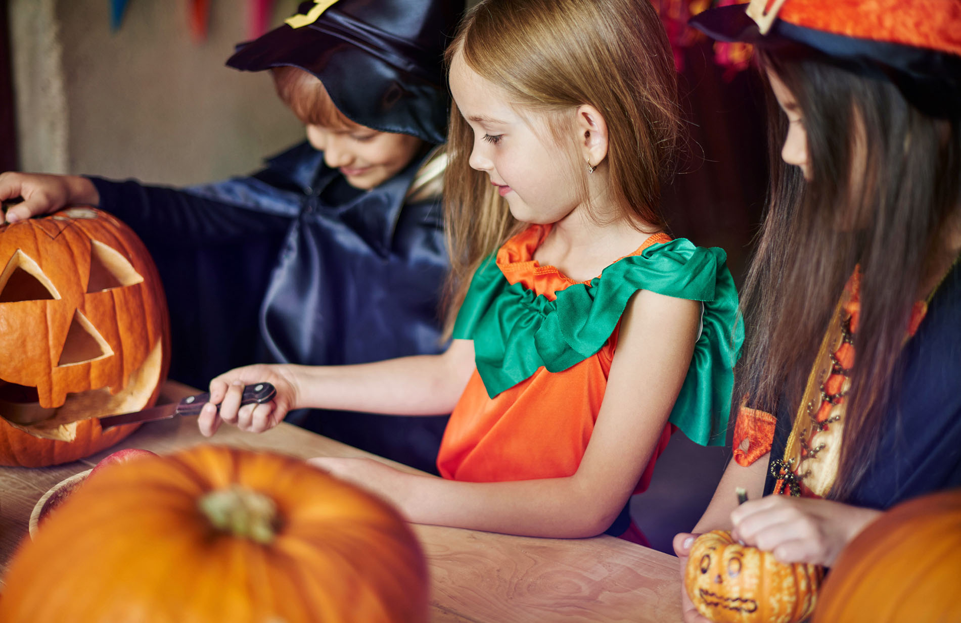 Focus children carving some shapes on the pumpkin
