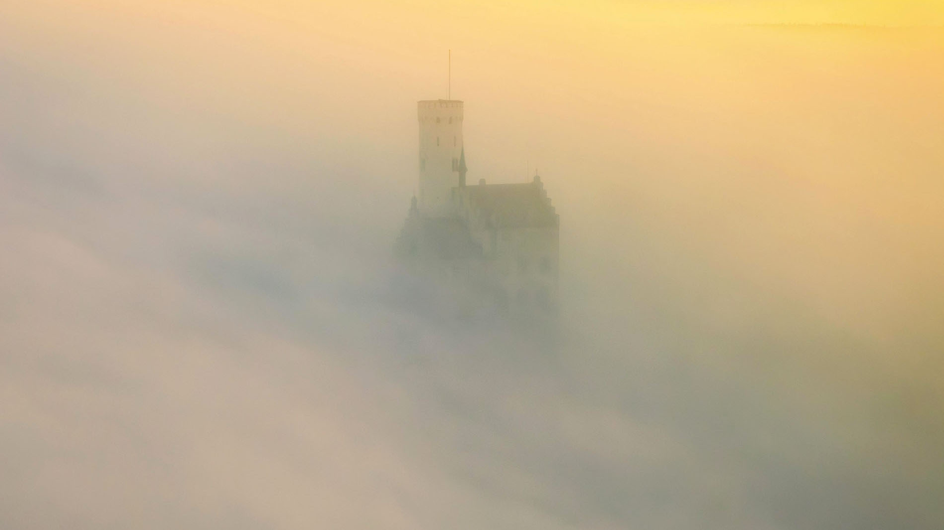 Castle shrouded in mist in the soft light of a sunrise, Lichtenstein Castle, Lichtenstein, Swabian Alb, Germany
