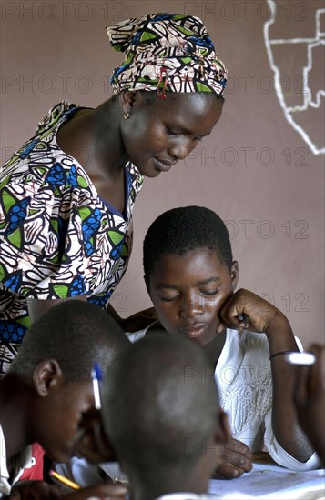 Institutrice africaine corrigeant les cahiers d'un élève, 2004