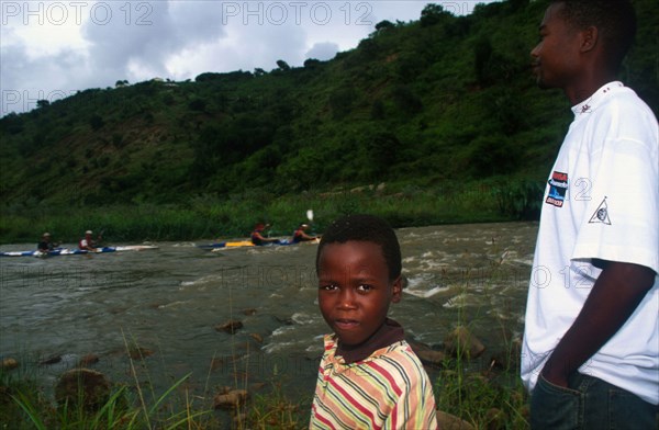 young man and boy in foreground with canoes on river in backgrou