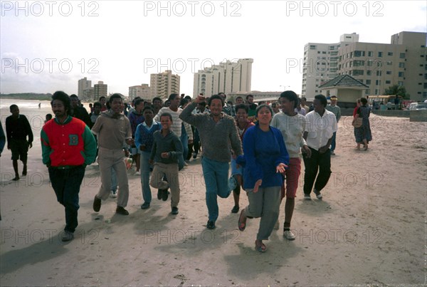 1989, The Strand, Cape Town, South Africa

coloured people, demonstrations against apartheid, beach demonstrations, cars, shops, beach, multiracial