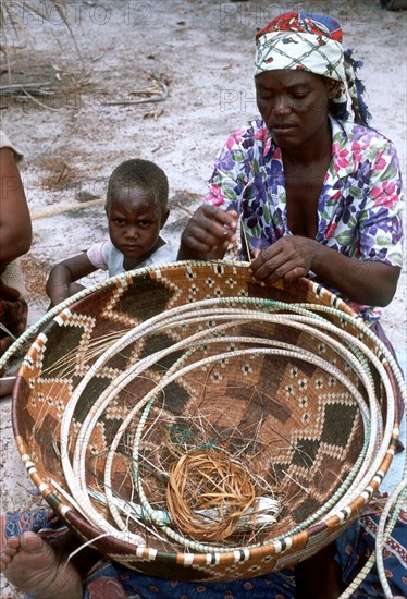 Lady weaving a large basket.
