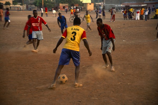 In the suburb of Corofina Nord, Bamako, Mali, young people gather in the late afternoon at a large dusty field to play sport - basketball and soccer - socialise, and play. The field seems to be the centre of social life in the area. 

Young men play a game of soccer in the dust
