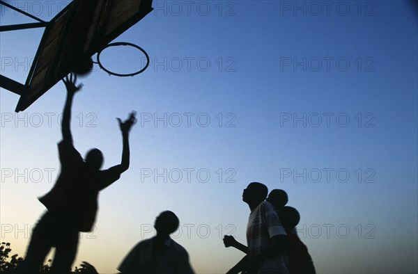 In the suburb of Corofina Nord, Bamako, Mali, young people gather in the late afternoon at a large dusty field to play sport - basketball and soccer - socialise, and play. The field seems to be the centre of social life in the area. 

Young men shoot hoops. Basketball seems to be big in this community.