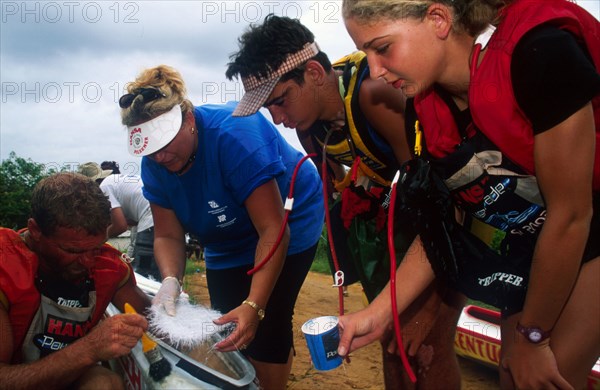 three persons on the right look on as one on the left repairs a