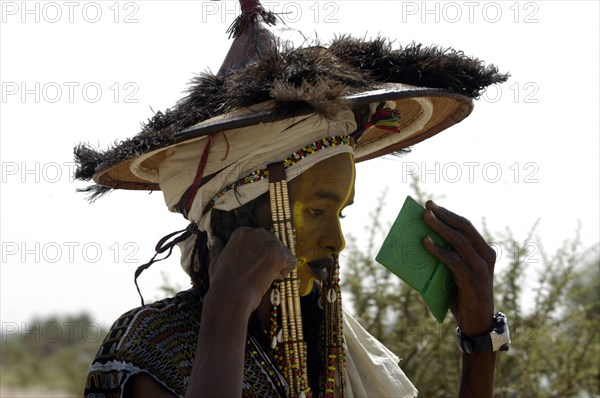 Wodaabe men examine their appearance in handmirrors at a festival in InGall, near Agadez in Niger on Friday Sept. 26, 2003. The Wodaabe, a nomadic West African tribe, value male beauty and are taught from an early age to look into mirrors to consider their appearance. The Wodaabe men perform a dance, showing off the whiteness of their teeth and eyes, to compete for honour and selection as the most beautiful man by women of the tribe at a festival celebrated at the end of the rainy season.  (Photo/Christine Nesbitt)