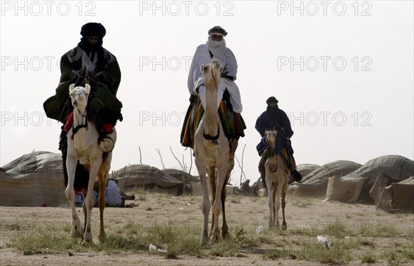 Nomads are seen on camels at the Salt Cure festival drawing nomads from all over the region to InGall, near Agadez in Niger on Thursday Sept. 25, 2003.  The Wodaabe men perform a dance, showing off the whiteness of their teeth and eyes, to compete for honour and selection as the most beautiful man by women of the tribe at the festival celebrated at the end of the rainy season. (Photo/Christine Nesbitt)