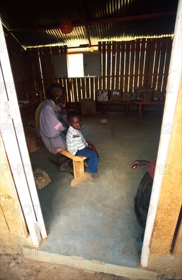 A Samburu child waits with his father or grandfather for medical attention at a mobile clinic set up in a school in the town of Wamba. Samburu men later on in life take young brides in their teens