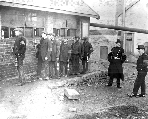 Strike-breaking coal miners in the Rhondda Valley, Wales, with their lamps before going down the pit. They are wearing khaki-coloured arm bands with the crown stamped on them, known as the Kakhi badge of Courage.