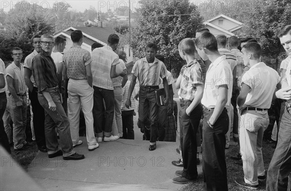 Line of African American boys walking through a crowd of white boys