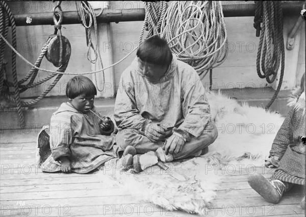 Native American child and man sitting on deck of a ship
