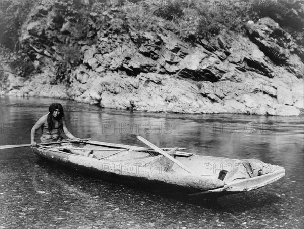 Native American Yurok Indian fisherman paddling a canoe on Trinity River