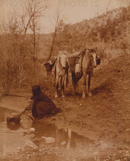 An Apache fills a container with water