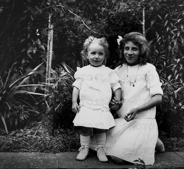 Two young French girls play in a garden