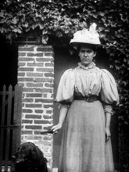 French woman stands next to a doorway with a dog