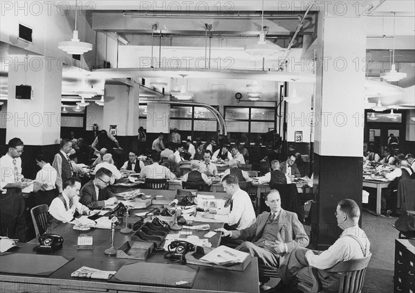 journalists sitting in a news room at an American newspaper office circa 1945