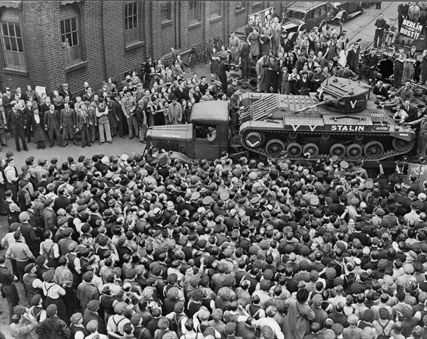 Crowds of people and a guard of honour of tanks