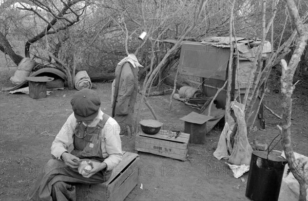 White migrant worker living in camp with two other migrant men. 19390101.