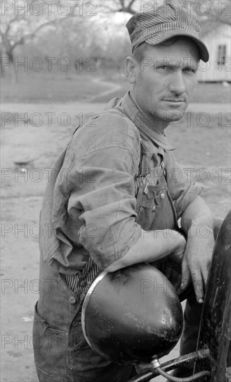 White migrant worker leaning on headlamp of his car near Harlingen