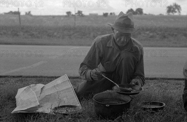 Migrant agricultural worker dishing up the noonday lunch of blackberry pie while camped by the roadside east of Fort Gibson, Muskogee County, Oklahoma By Russell Lee, 1903-1986, photographer Date 19390101