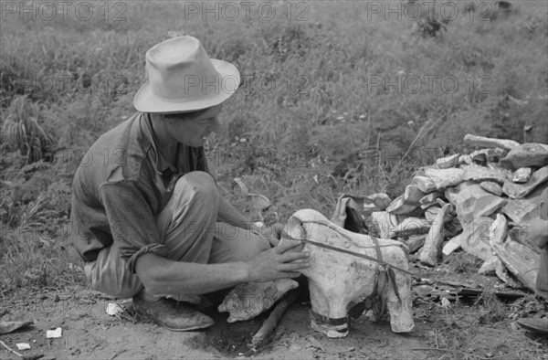 Itinerant statue maker putting together the pieces of a mould for one of his statues. 19390101