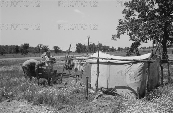 Camp of migratory workers who move along the road pushing their belongings in a cart, camped near Vian, Sequoya County, Oklahoma 19390101.
