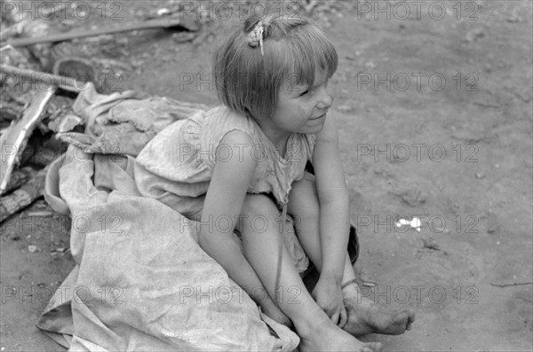 Child of white migrant worker sitting on cotton pickers' sacks near Harlingen, Texas by Russell Lee, 1903-1986, dated 19390101.