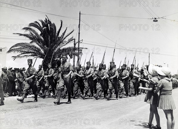 Photograph of two children waving as French troops march along Avenue Gambetta, during the allied victory parade