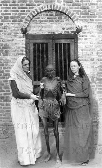 Photographic print of an emaciated famine victim standing with Miss Neil and an unidentified woman