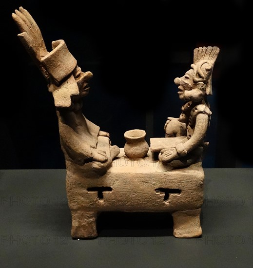 Mayan figurine depicting two men sitting on a bench. 600-900AD