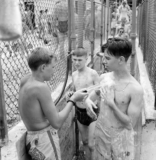 Glen Echo, Maryland, USA. An attendant washing the sand from people who are going to the swimming pool for the swimming pool at the Glen Echo amusement park.