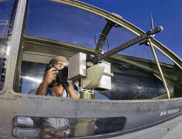 World War Two US Navy ordnance man, with a M1919 Browning machine gun next to a PBY Catalina aircraft 1942