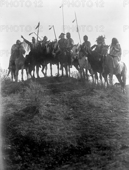 Photographic print of eight Crow Indians on horseback, silhouetted on top of hill