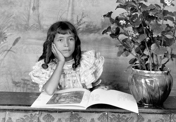 Daughter of Thomas E Askew, head-and-shoulders portrait, seated, right hand on cheek, with open book.