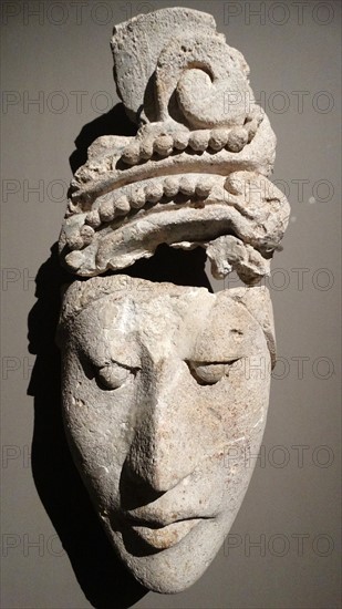 Mayan stucco portrait head of a female dignitary, with stylised hair.