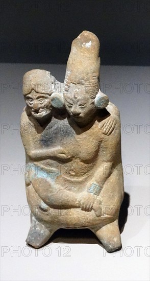 Mayan ceramic figurine of a young woman in the embrace of an old man.