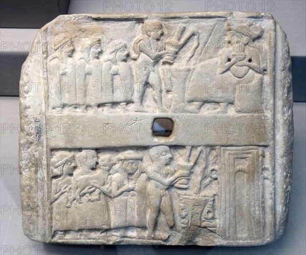 Square stone plaque with holes through the centre carved in relief