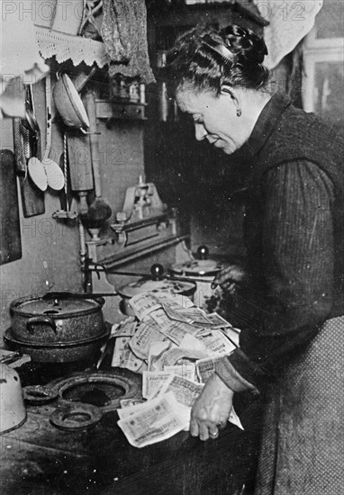 German woman starting a fire with a pile of marks