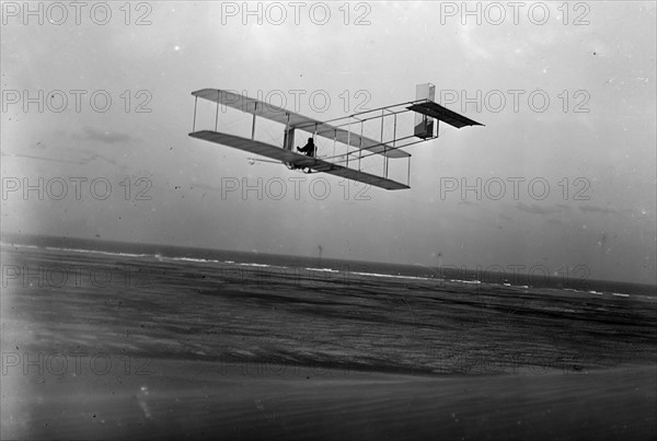 Three-quarter left rear view of glider in flight at Kitty Hawk