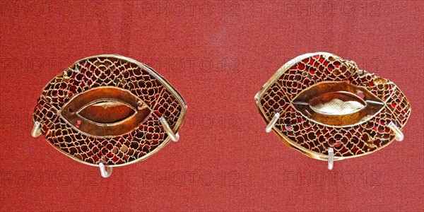 Anglo Saxon metalwork; 5th-6th Century AD. Pair of eye-shaped mounts, with cloisonné garnets