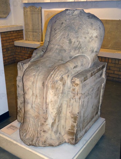 Seated male figure wearing a decorated sleeved chiton and himation marble