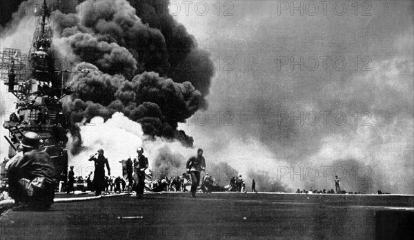 Photograph of the USS Bunker Hill taking two kamikazes