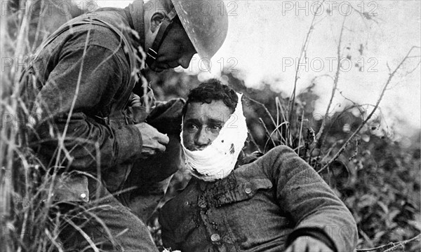 Photograph of a wounded American soldier, receiving first-aid treatment during World War One