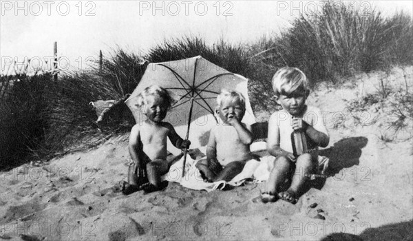 Vintage photograph of three children on a sandy shore 1930