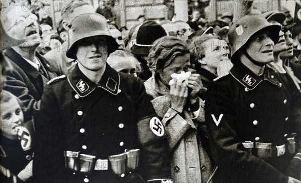 Austrian civilians standing behind an S.S. trooper during Germany Occupation of Austria