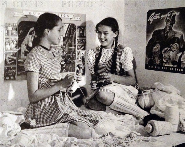 Young girls learning to knit by recycling material in order to make new clothing