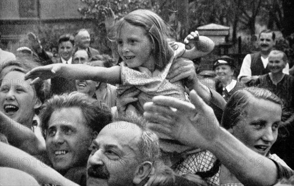 Enthusiastic crowds wave and salute Adolf Hitler at a parade in 1934