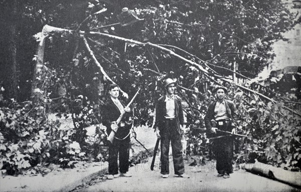 Republican fighters wait next to a fallen tree in Barcelona