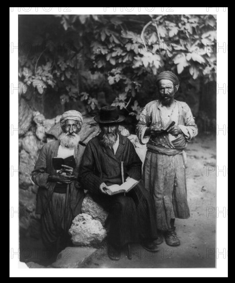 Three elderly men holding books